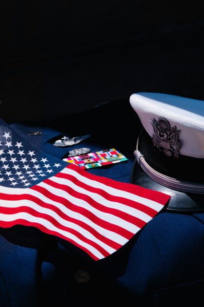 U.S. military dress cap resting on a folded American flag, symbolizing honor and veteran service.