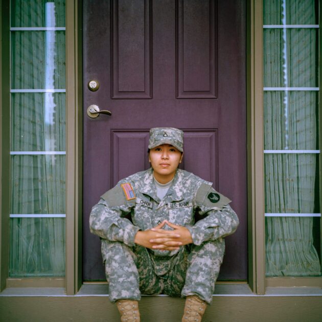 U.S. Army service member sitting on a doorstep in uniform, representing veterans eligible for the GI Bill.