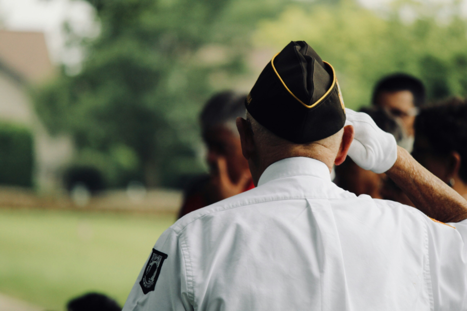 Veteran in uniform saluting during a ceremony, representing the dignity and service supported by the VA healthcare system.