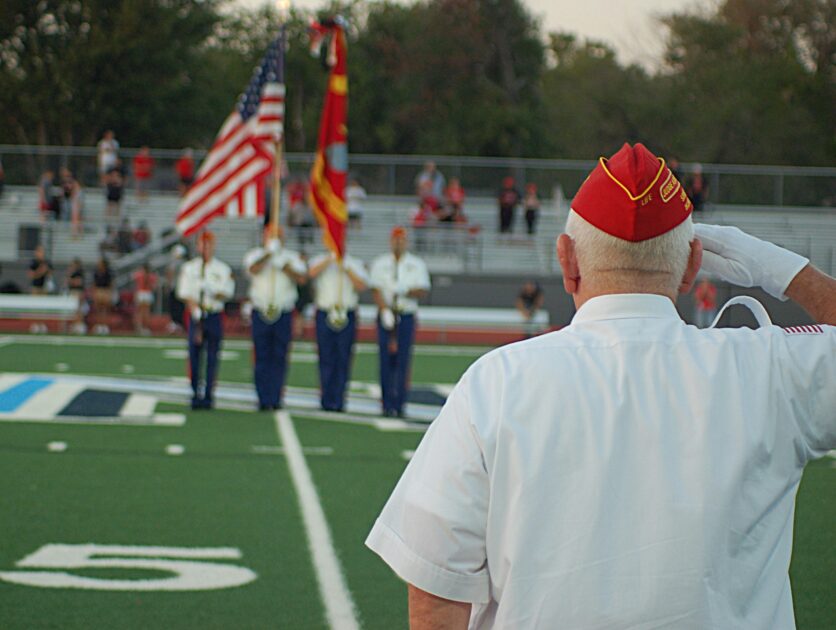 Service member in uniform saluting a color guard, representing the importance of military discharge status.