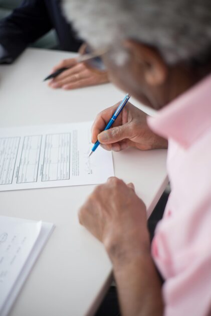 Person signing financial documents, representing how to set up a Payable on Death (POD) account